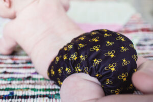 Baba+Boo Bees a black reusable nappy with gold bees on a baby